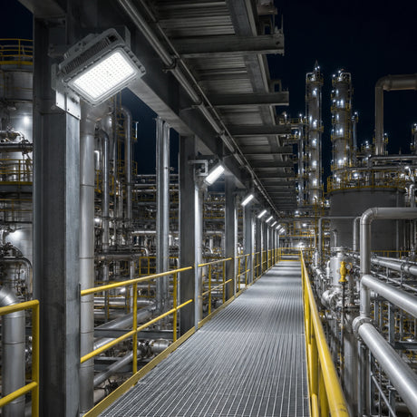 Row of 150W C1D1 square LED explosion proof flood lights delivering 21,000 lumens of 5000K illumination along a refinery walkway.
