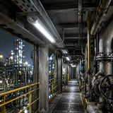 C1D2 linear LED explosion proof light illuminating a refinery catwalk with pipes at night