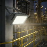 Explosion proof LED flood light wall mounted on industrial oil refinery structure illuminating walkway at night