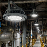 Industrial facility walkway brightly illuminated by high-output LED high bay lights, showcasing uniform lighting and safety compliance in hazardous areas.